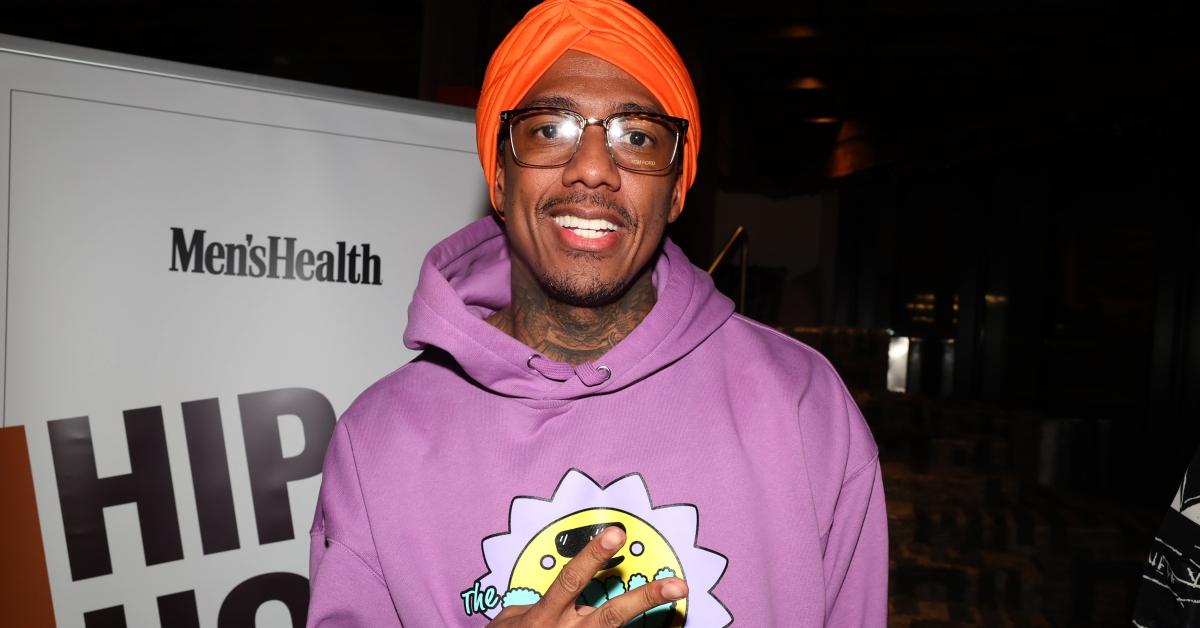 Nick Cannon wears a purple hood and orange burban and smiles.