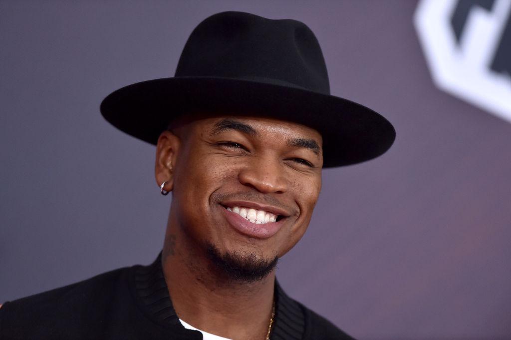 Ne-Yo wears a black fedora and smiles.