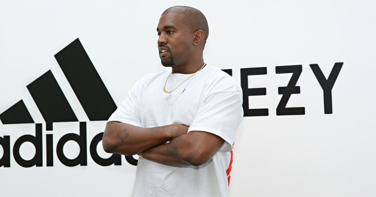 Yeezy posing infront of Adidas sign