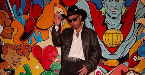 Anderson .Paak posing in front of a cartoon mural