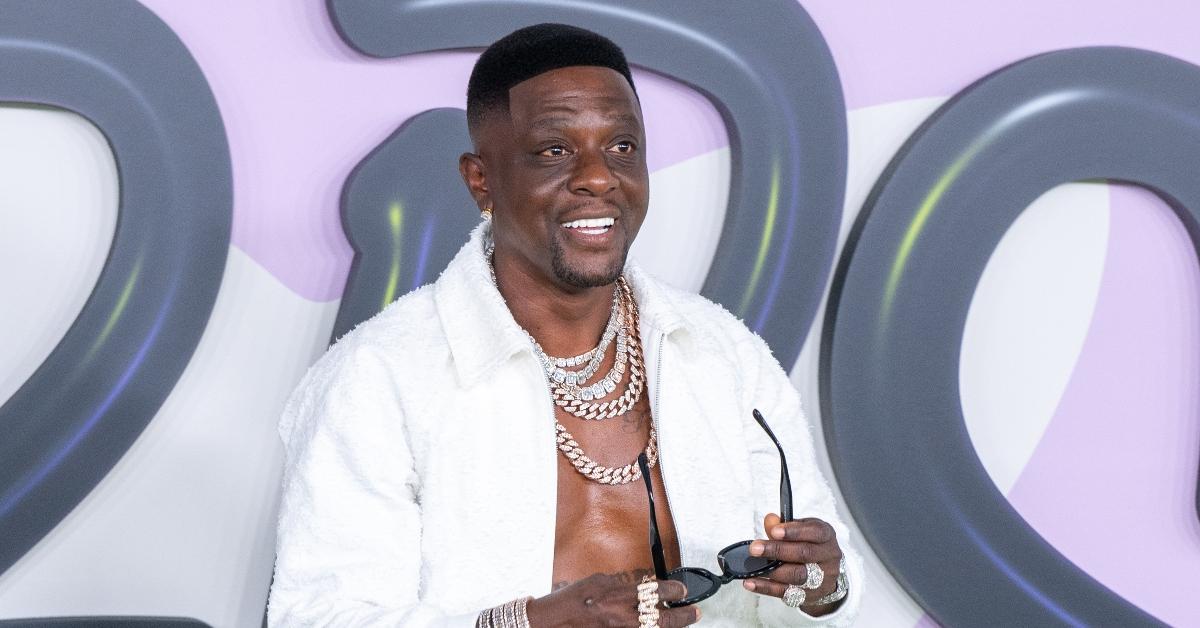 Boosie Badazz with silver chains and white jacket smiling at the camera