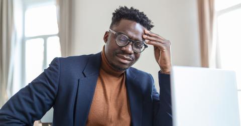 Black man dressed in business casual wear looks stressed out.