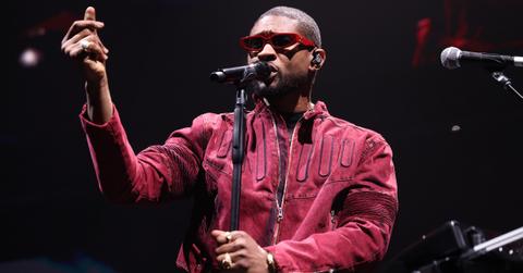 Usher performs on stage wearing red sunglasses and jacket.