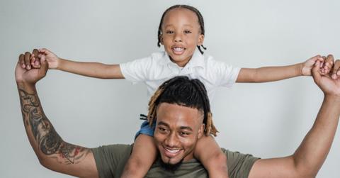 Son sits on his father's shoulders.