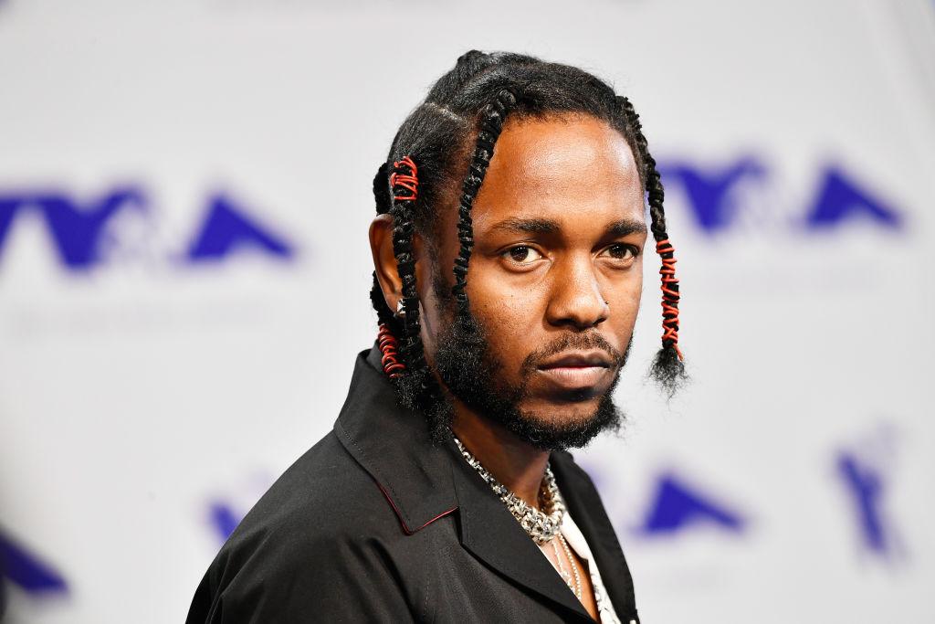 Kendrick Lamar wears braids with red rubberbands and a black shirt at the MTV VMAs.