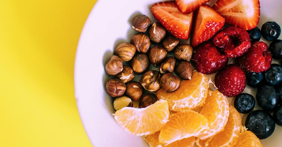 A bowl of oranges, berries, chickpeas, and blueberries.