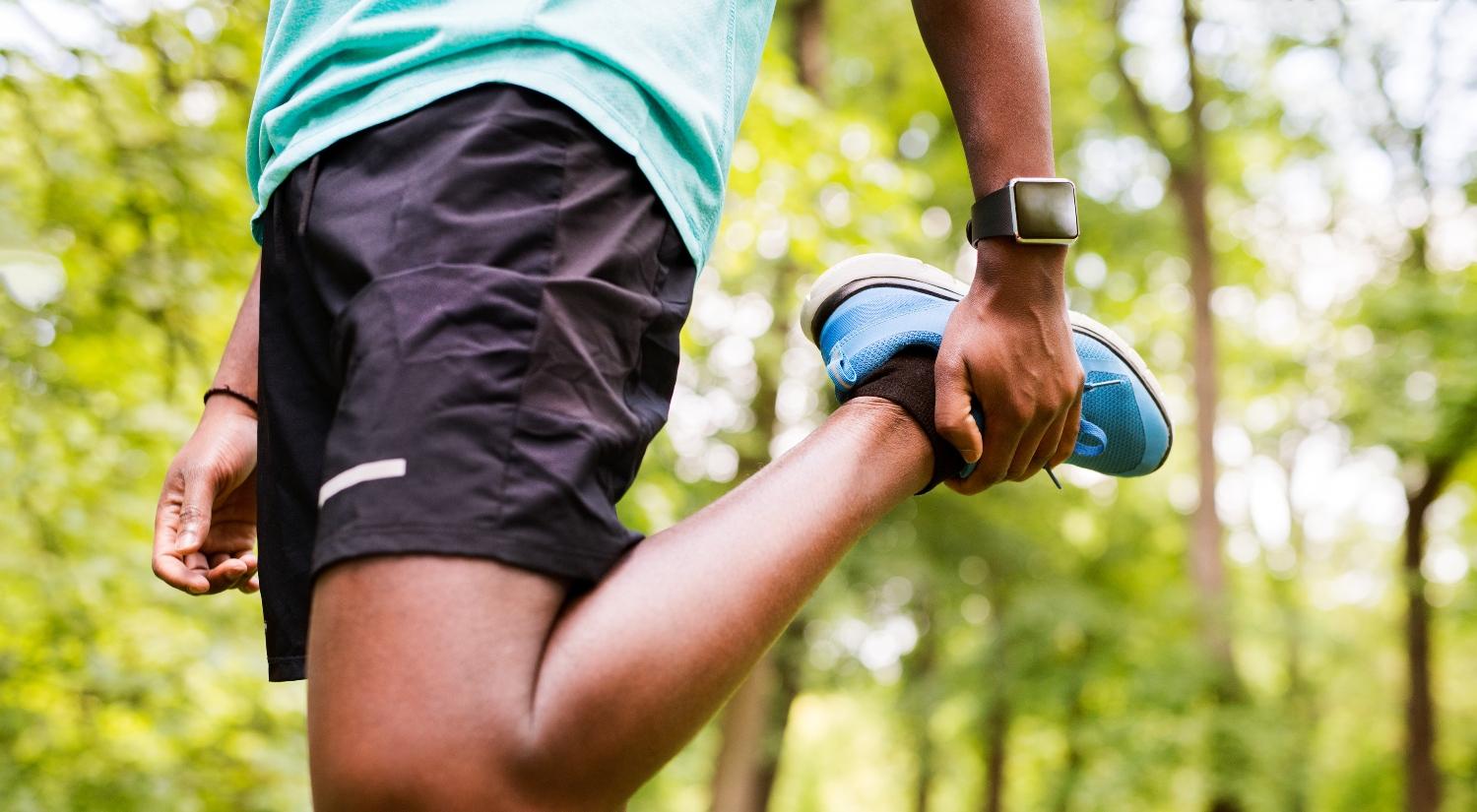 man in park warming up and stretching arms and legs before training