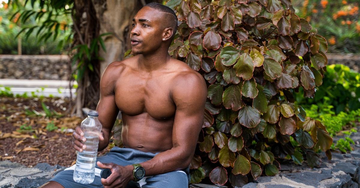 a black man drinking a bottle of water after a workout