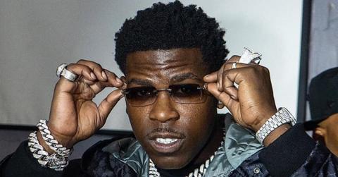 Casanova holding sunglasses with iced out jewelry