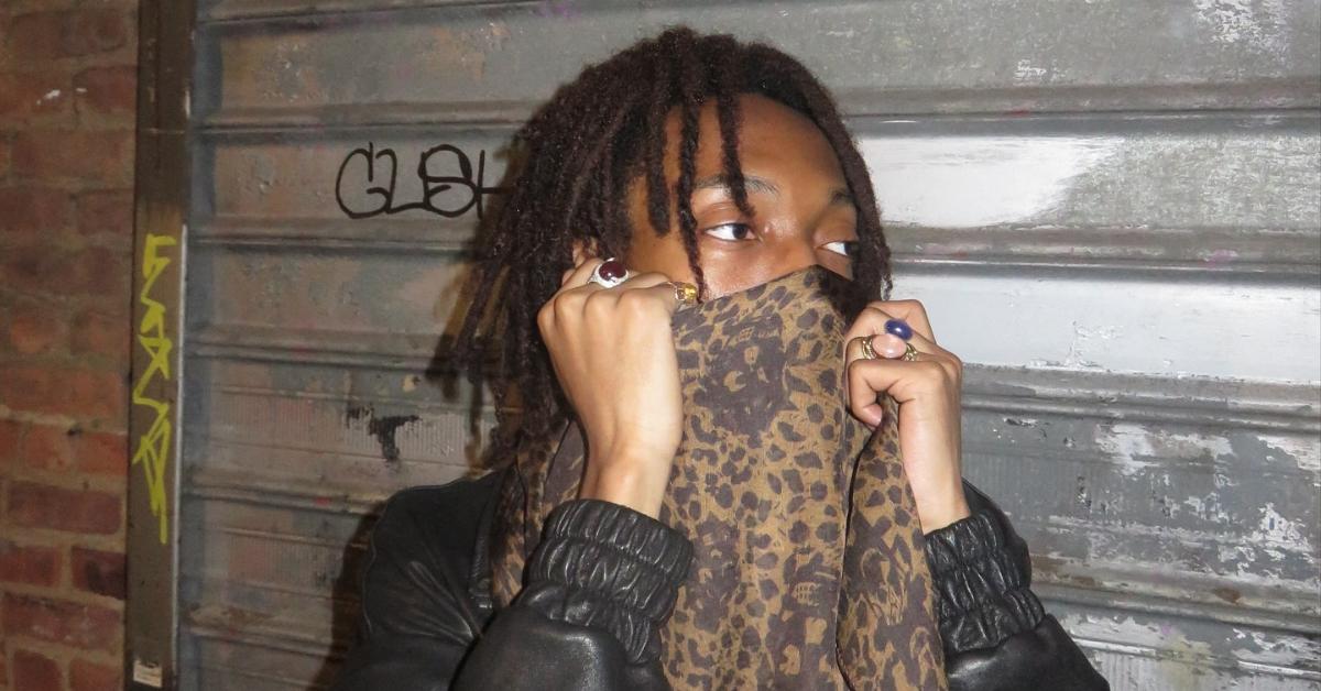 Lil Tecca outside with leopard print scarf around his face