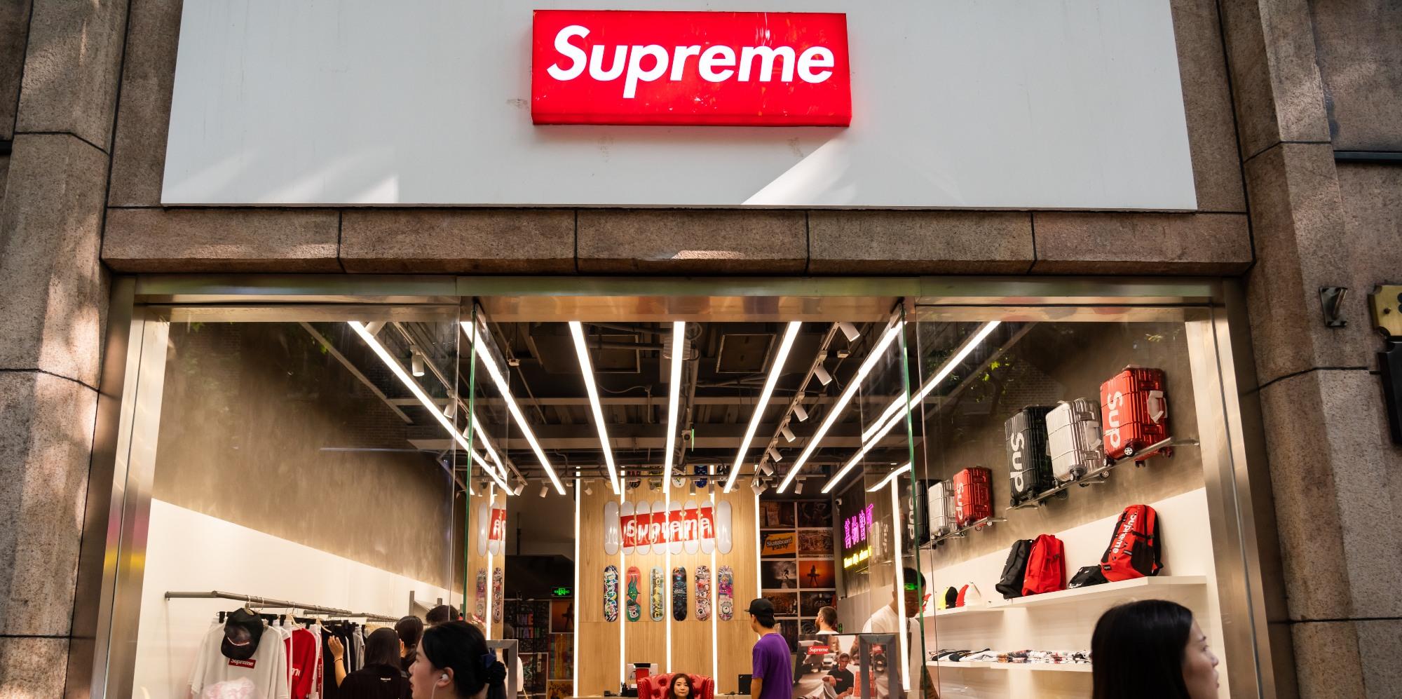 pedestrians walk past an american skateboarding shop and clothing brand supreme store