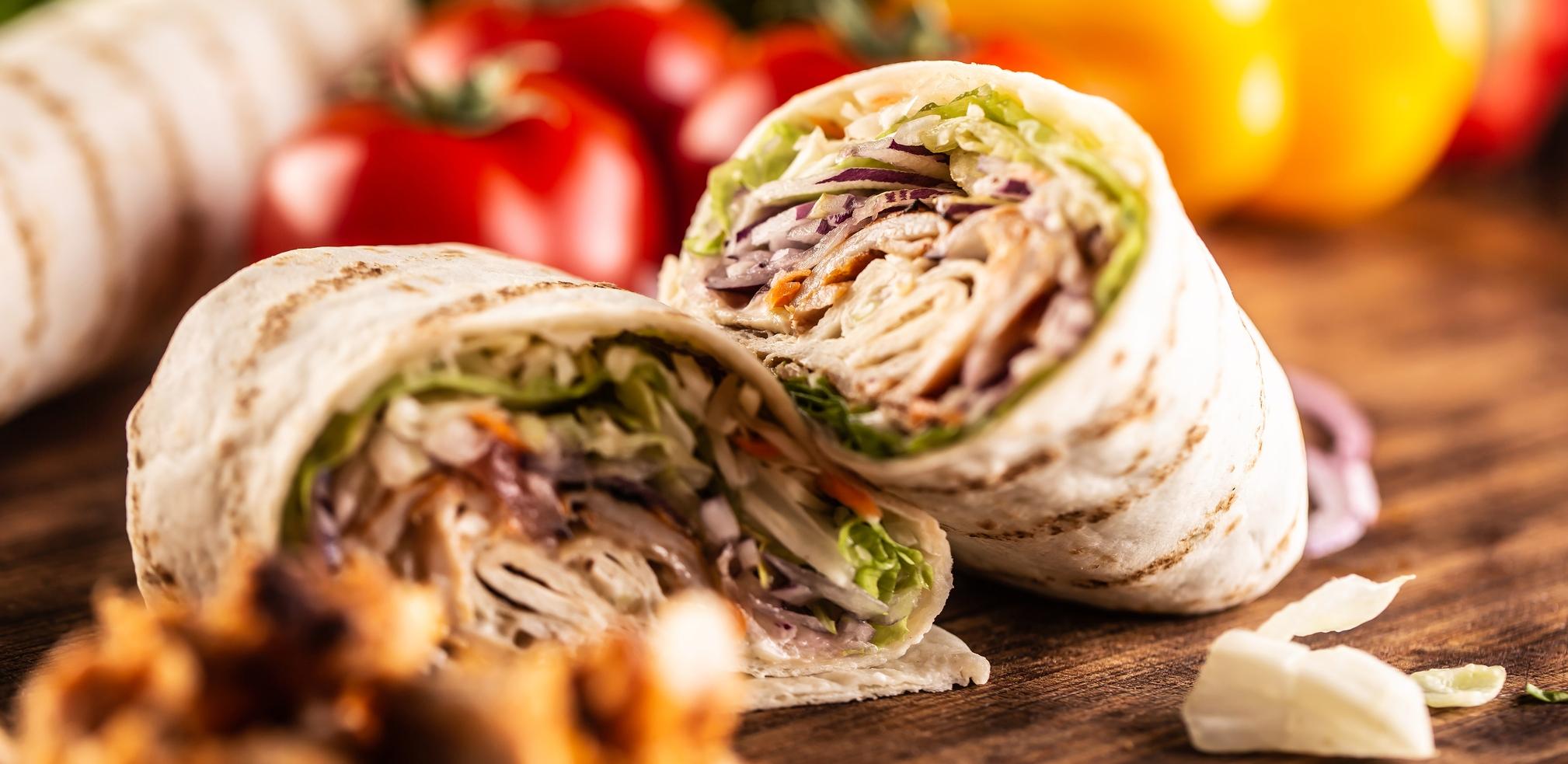 meat filled tortilla wraps on a table with vegetables