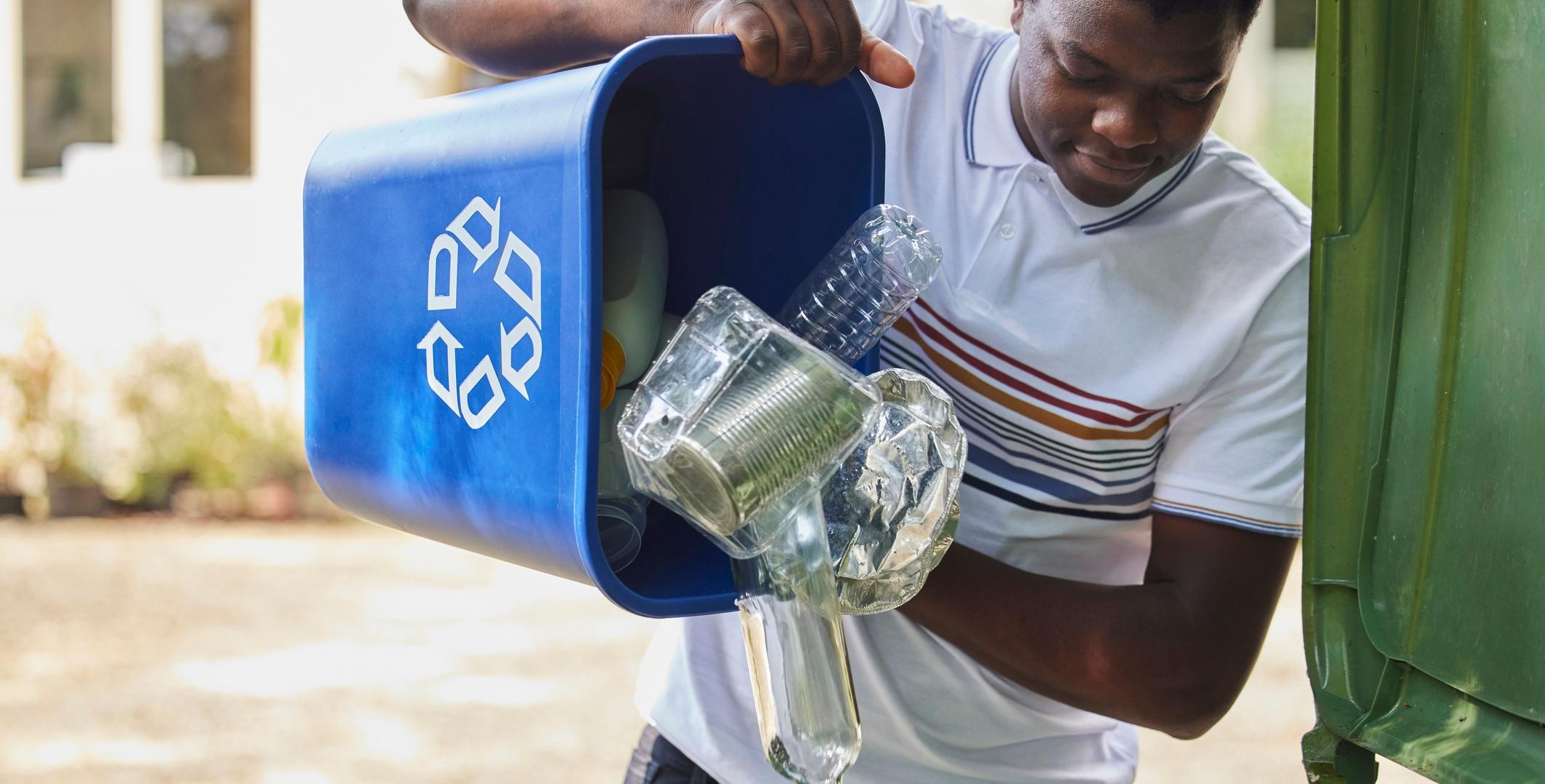 young man emptying household recycling into green bin