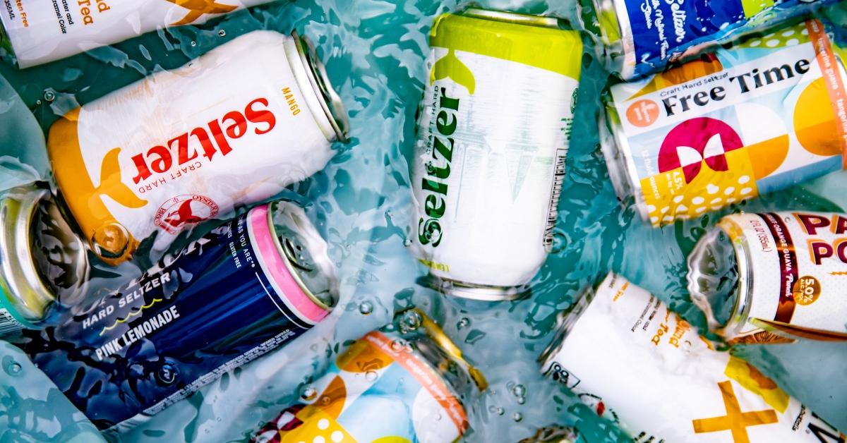 A collection of colorful canned hard seltzers and teas in a pool of water.