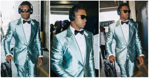 Russell Wilson wears satin baby blue tuxedo walking into a stadium arena before a game.