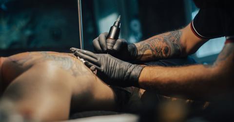 Professional tattooer tattoos a man's back.