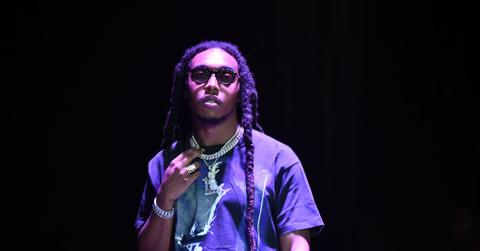 Takeoff from the migos wears glasses and a diamond chain on stage.