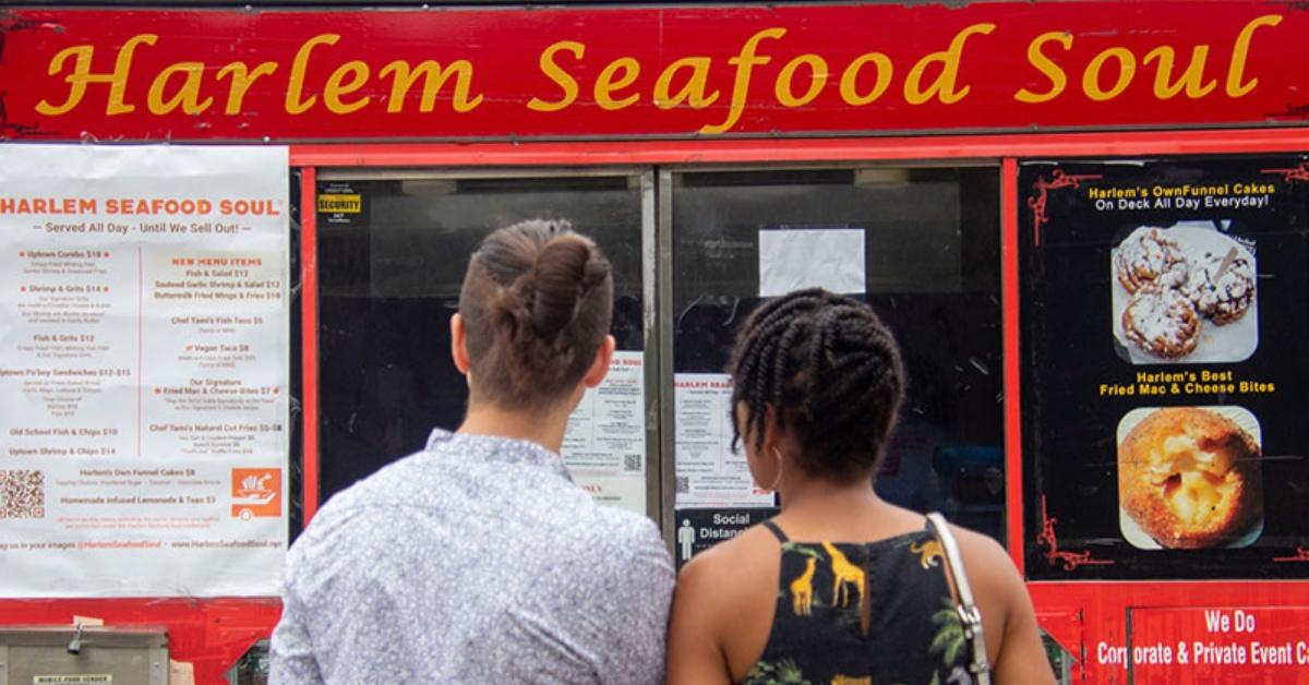 People waiting to order in front of Harlem Seafood Soul food truck.