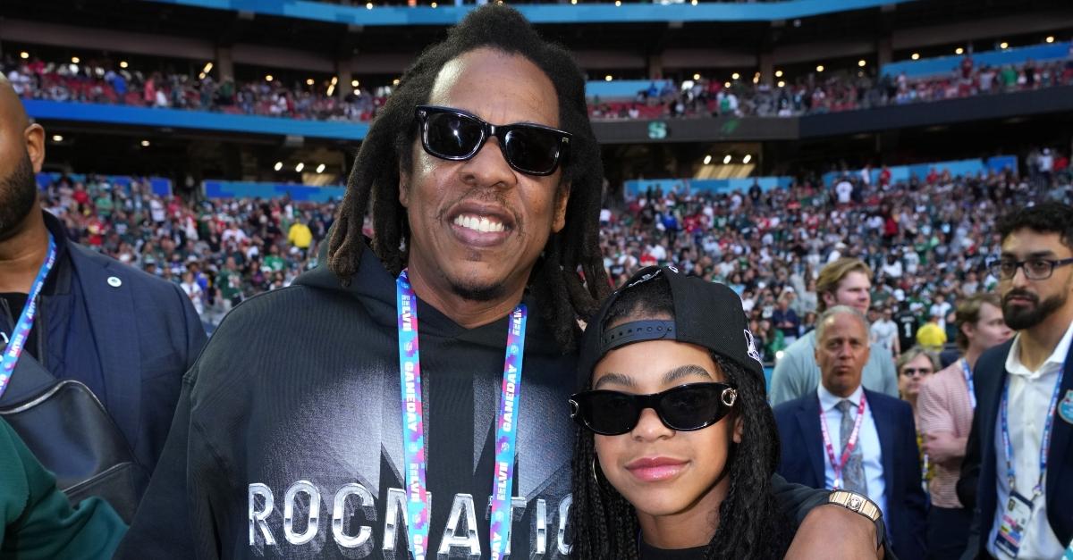 Jay-Z and Blue Ivy wearing matching back hoodies and sunglasses at Super Bowl LLVI.