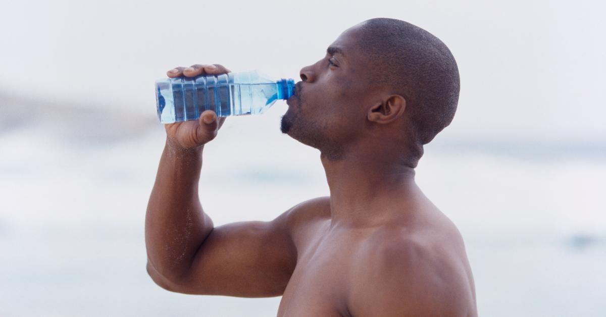 A Black man enjoying a bottle of water outside