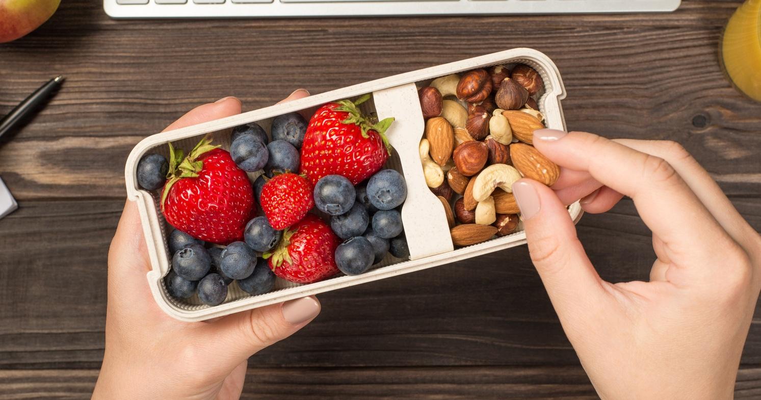 womans hands holding lunchbox with healthy meal nuts and berries