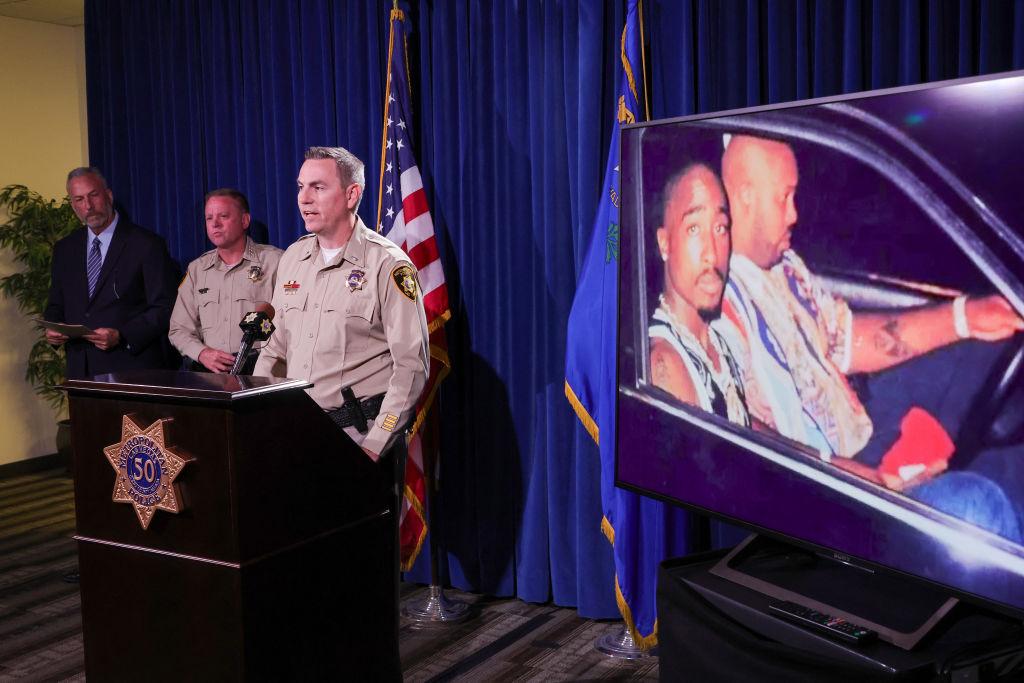 An image on a television monitor shows a photo of Tupac Shakur (L) and Marion "Suge" Knight Jr. in a car in Las Vegas the night Shakur was killed as (L-R) Clark County District Attorney Steve Wolfson, Clark County Sheriff Kevin McMahill and Las Vegas Metropolitan Police Department Lt. Jason Johansson hold a news conference at the LVMPD headquarters on the arrest and indictment of Duane "Keefe D" Davis for the 1996 murder of Shakur.