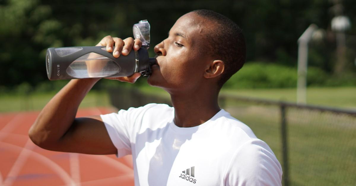 Black male drinking water from a water bottle