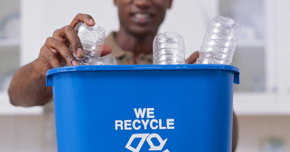 Man putting plastic bottle in recycle bin.