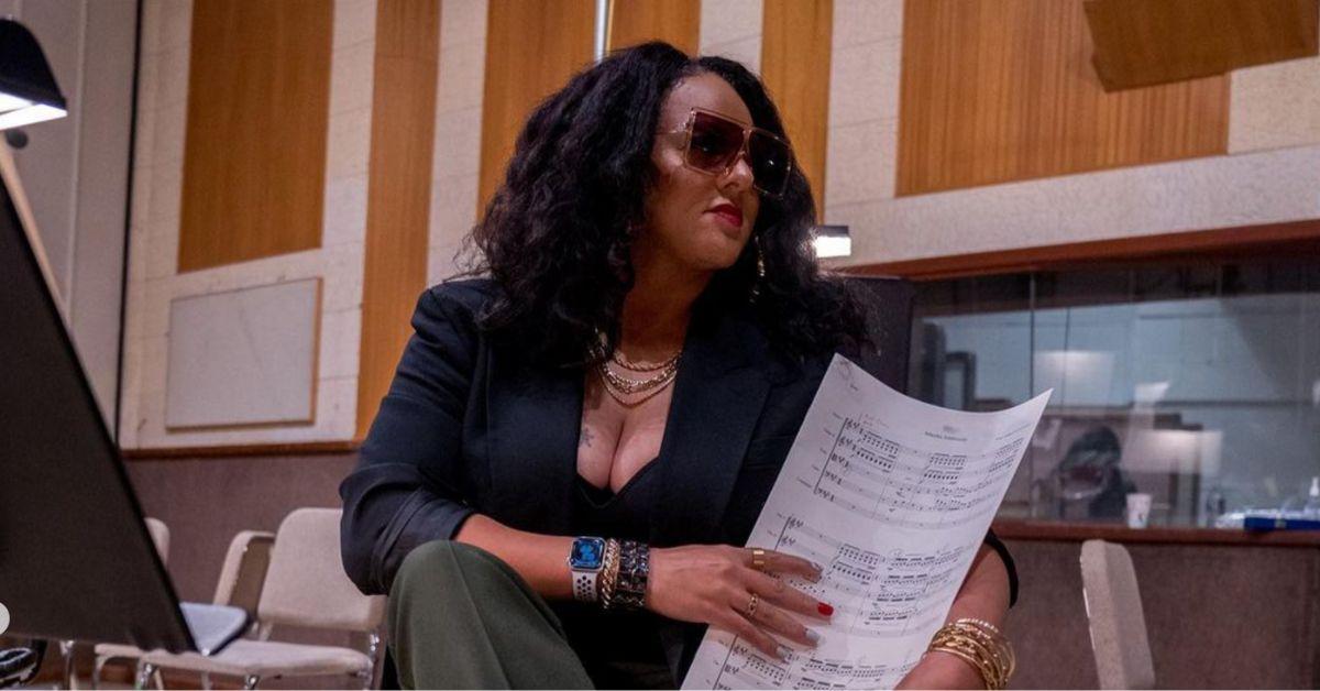 Marsha Ambrosius holds sheet music while seated in a recording studio