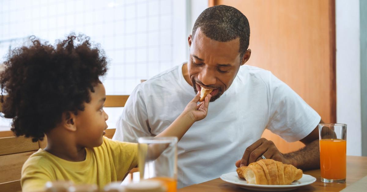 Boy feeding Croissant or bread father.