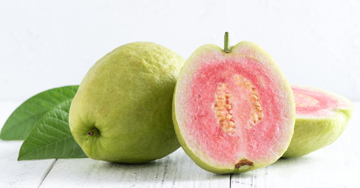 delicious beautiful red guava with fresh green leaves on a white table