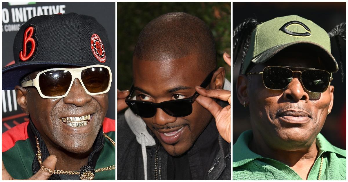 Flavor Flav wears gold grill and chain wearing a black and red hat on the red carpet; Ray J tilts his shades and looks over then and smiles; Coolio wears a green hat and sunglasses on stage.