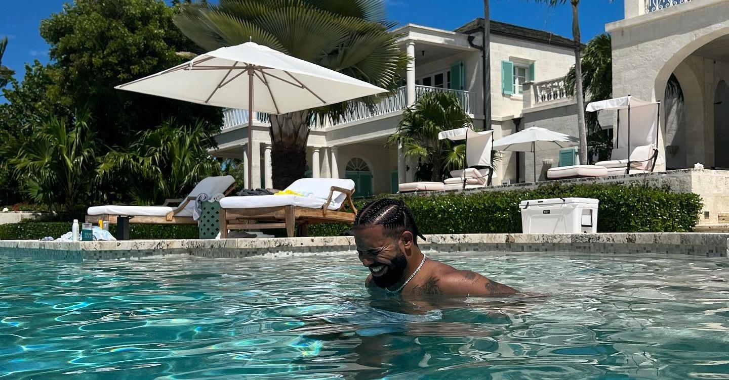 Drake smiles while swimming in a pool on vacation.